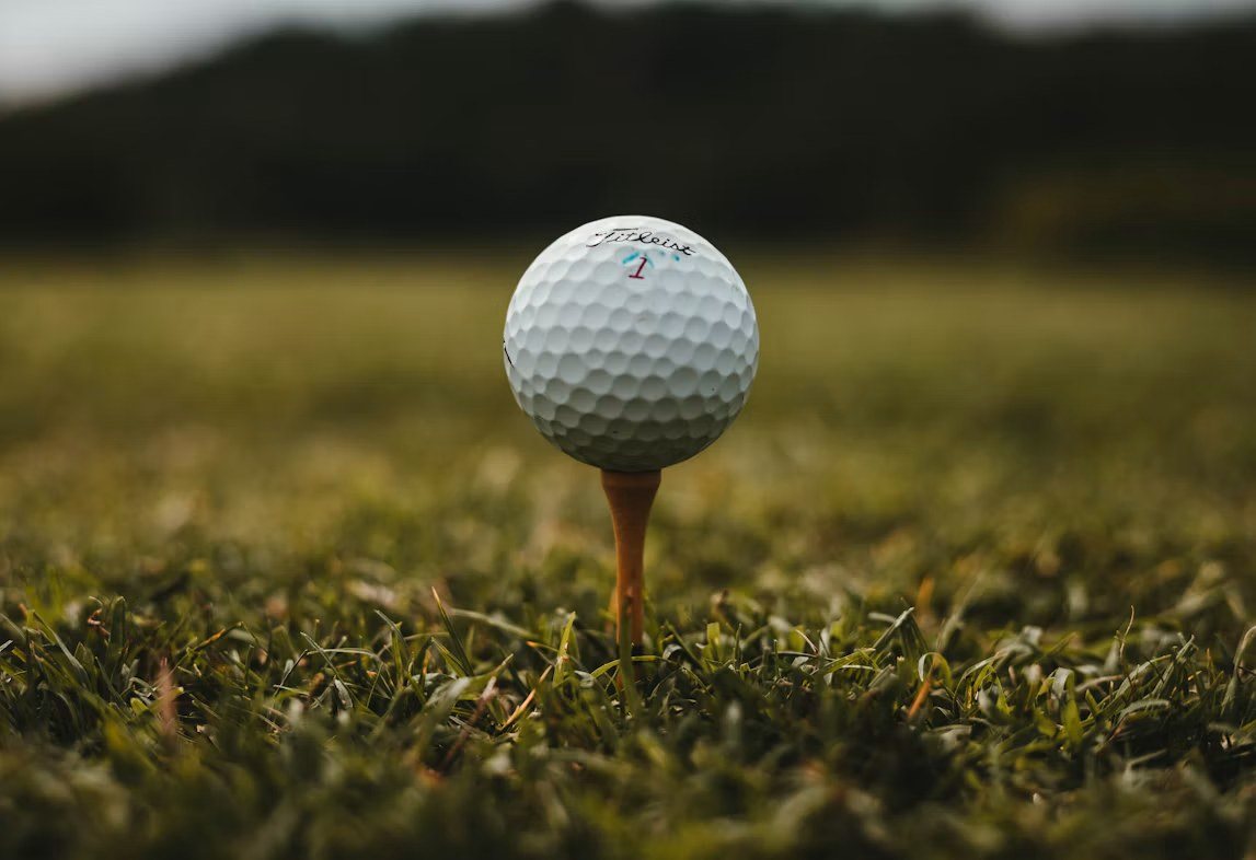 A golf ball on a tee in short grass, close up