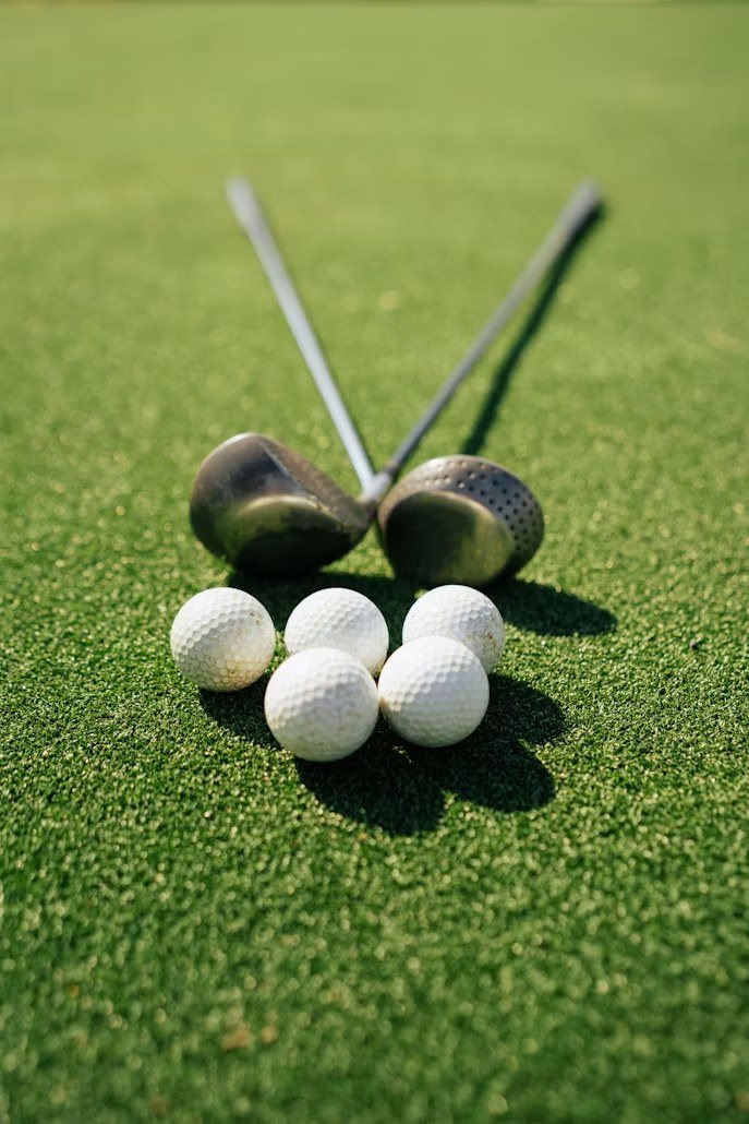 Two golf clubs crossed on the green with white golf balls
